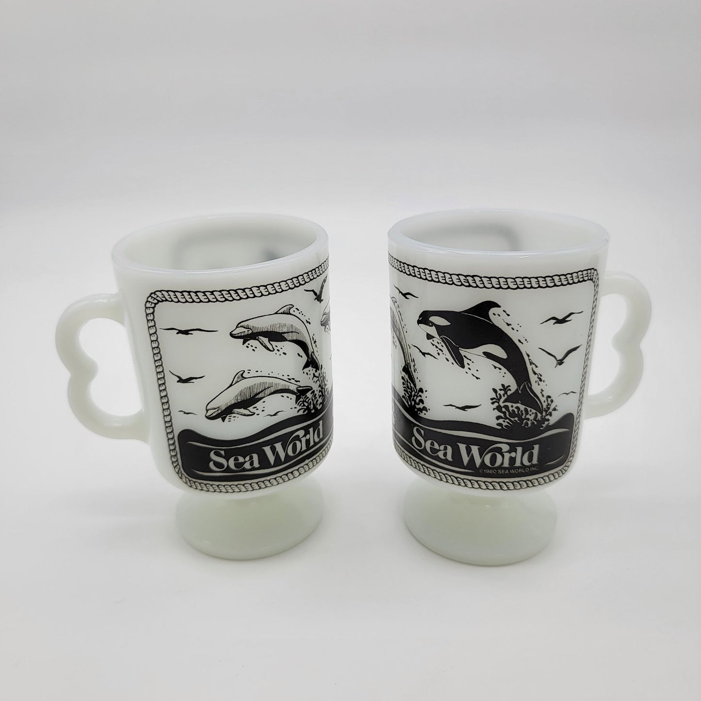 Pair of 1980 Vintage Fire King Milk Glass Sea World Footed Mugs Dolphin Orca Design